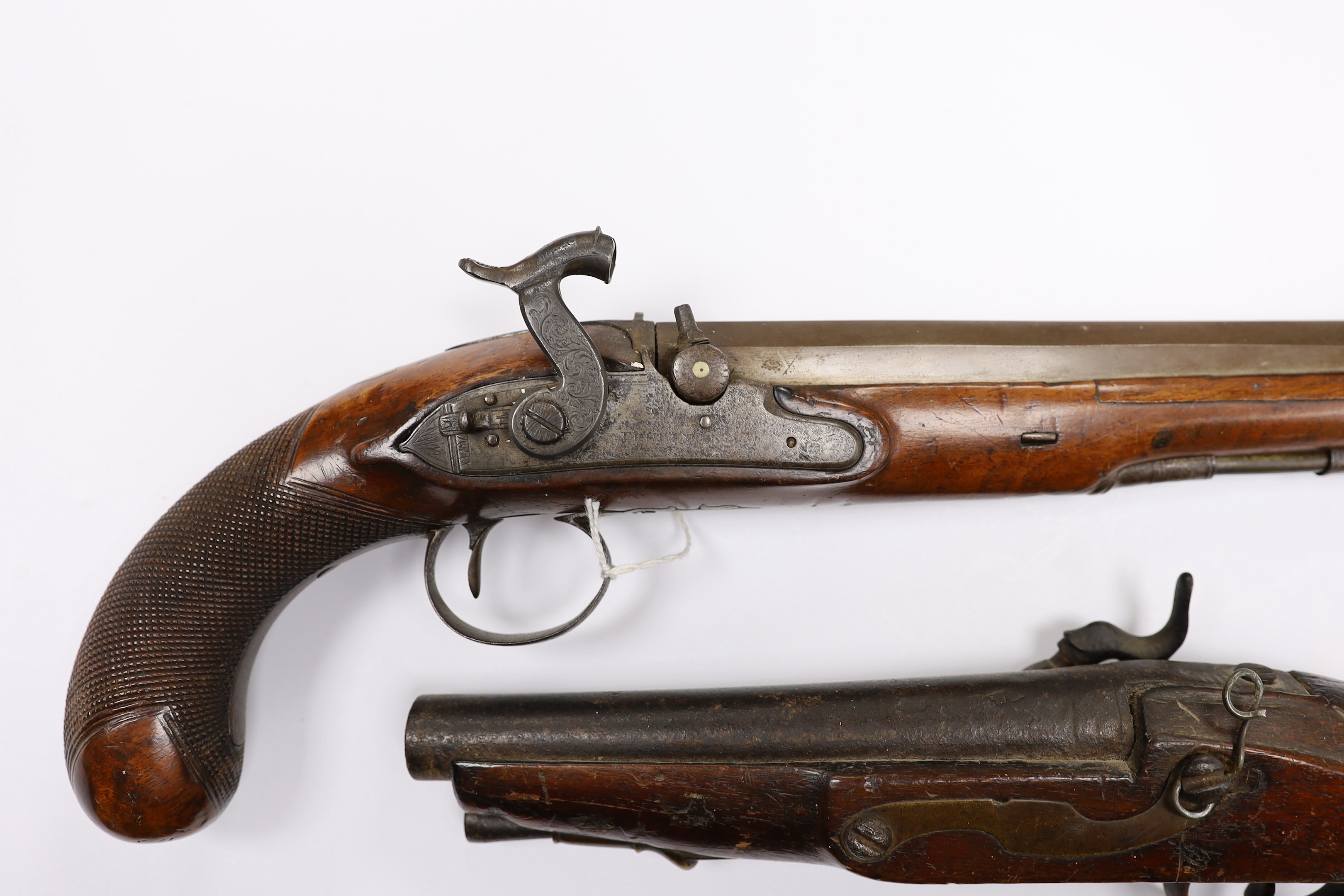 Two percussion 19th century pistols, both converted from flintlock, the larger example with engraved lock and hammer, octagonal barrel and chequered grip, together with a smaller overcoat pistol, fully stocked with brass
